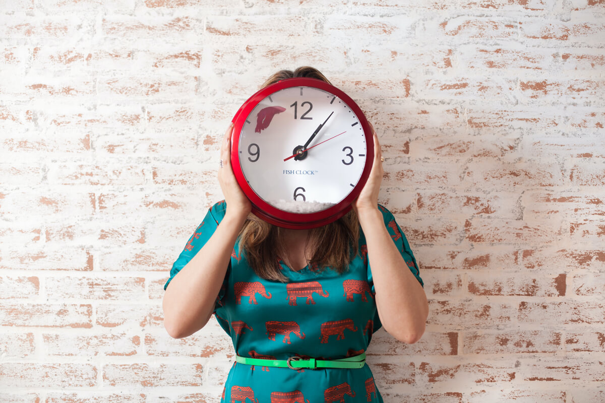 Female holding a clock showing a timeline for selling a home